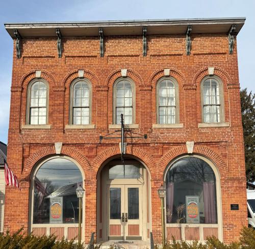 a red brick building with five windows and a flag at Wenzil Taylor Building in Spillville