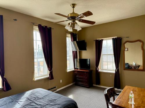 a bedroom with a ceiling fan and a bed and a table at Wenzil Taylor Building in Spillville