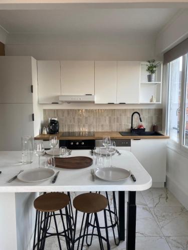 une cuisine avec un îlot blanc et trois tabourets de bar dans l'établissement Appartement cosy en centre-ville, à Calais