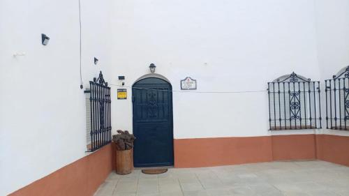 a black door in a white wall with two gates at Alojamiento La tinaja in Guadix