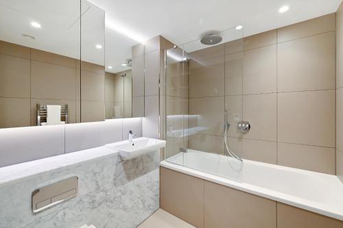 a bathroom with a tub and a sink and a mirror at Access Tower Hill in London