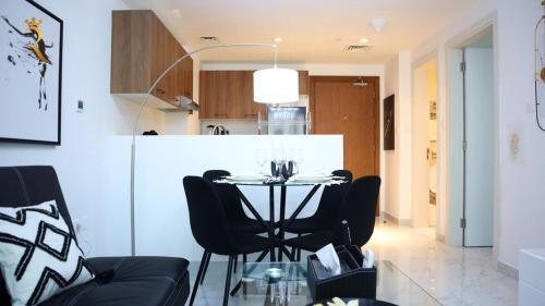 a dining room with a table and black chairs at Oasis Luxe 1BR - Stylish Luxury Stay Near Masdar Park & City Centre Masdar in Abu Dhabi