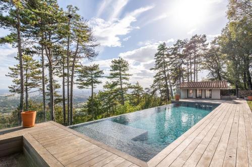 une piscine avec une terrasse en bois et une maison dans l'établissement Ermitage - Magnificent Villa with Panoramic View Saint-Cyr-au-Mont-d'Or, à Saint-Cyr-au-Mont-dʼOr