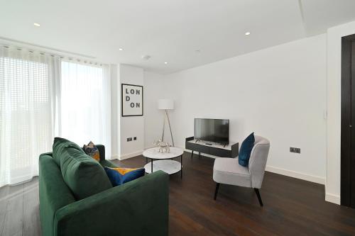a living room with a green couch and a television at Access Tower Hill in London