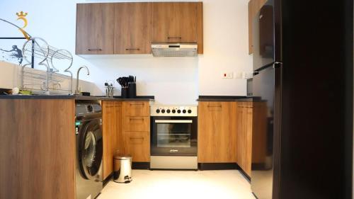 a kitchen with wooden cabinets and a washer and dryer at Oasis Luxe 1BR - Stylish Luxury Stay Near Masdar Park & City Centre Masdar in Abu Dhabi