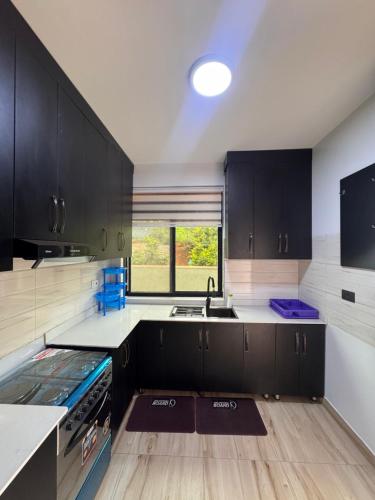 a kitchen with black cabinets and a sink at Rebero A3s apartment in Kigali