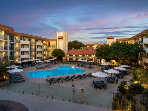 an outdoor pool with tables and umbrellas at night at Embassy Suites by Hilton Scottsdale Resort in Scottsdale