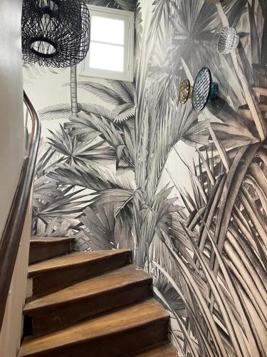 une fresque murale de palmiers sur un mur avec des escaliers dans l'établissement Charming studio, à Paris