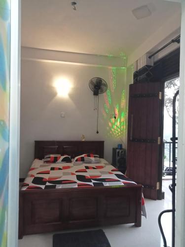 a bedroom with a bed with a red and white comforter at Devil mountain guest in Kalupahana