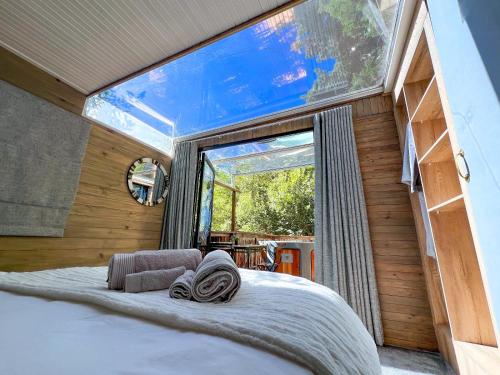 a bed in a room with a large window at The Cabins at Phantom Acres in Hout Bay