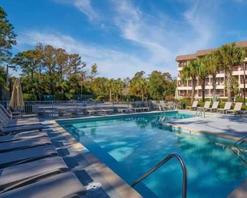 a swimming pool with lounge chairs and a hotel at Direct Luxury Oceanfront - On The Beach! Amazing Sunrises, 2 Pools & Bar! in Hilton Head Island