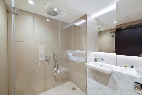 a bathroom with a shower and a sink and a mirror at Access Tower Hill in London