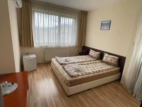 a bedroom with a bed and a large window at Къща за гости Александра in Dobrinishte