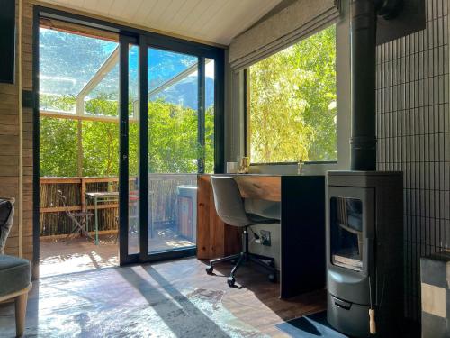 a room with a fireplace and a desk in a room with windows at The Cabins at Phantom Acres in Hout Bay