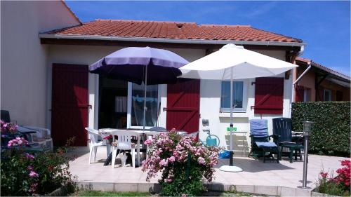 - deux parasols, des tables et des chaises sur une terrasse dans l'établissement VILLA 3 chbres Vue mer maison avec piscine ds residence proche commodites et plages de sable, à La Bernerie-en-Retz