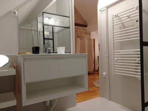 une salle de bain blanche avec un lavabo et un miroir dans l'établissement gite de séjour Vézelay La Romanella, à Asnières-sous-Bois