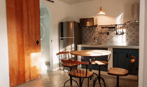 a kitchen with a table and chairs and a refrigerator at Villa Mykonos - Experiência Grega Exclusiva em Tiradentes - 5 Suítes de Luxo in Tiradentes