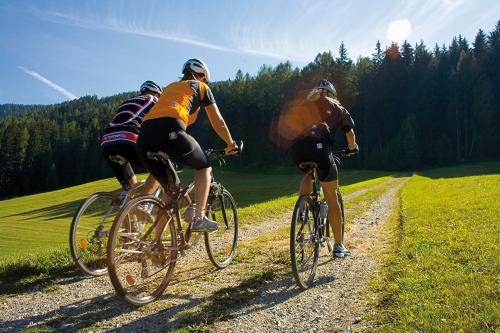 three people riding bikes down a dirt road at Boutique Hotel Am Park in Valdaora