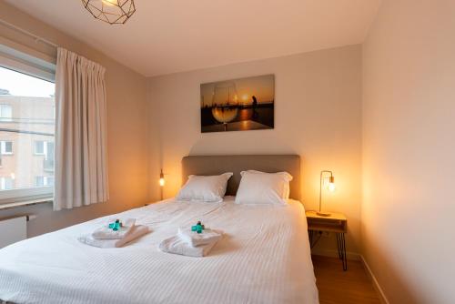 a bedroom with a white bed with two towels on it at Modern apartment with large terrace close to the sea in Ostend