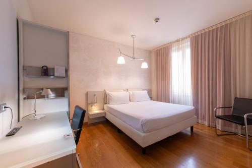 a hotel room with a white bed and a desk at Hotel Mercure Milano Solari in Milan