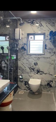 a bathroom with a white toilet and a window at Mai's Beach Resort in Malvan