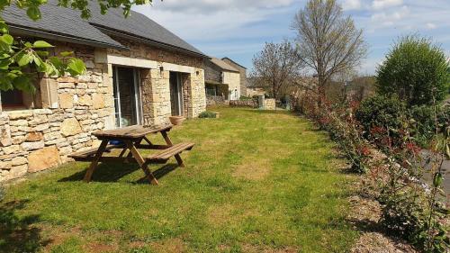 - une table de pique-nique en bois assise dans l'herbe à côté d'un bâtiment dans l'établissement Maison Gorges du Tarn, à Coquenas