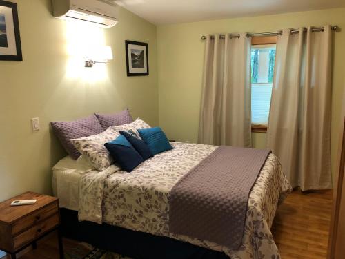 a bedroom with a bed with purple and blue pillows at The Bungalow -- Minutes from the Airport - on the Way to the Glacier in Juneau