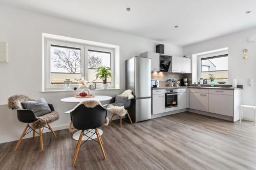 a white kitchen with a table and chairs in a room at Mika in Oesterdeichstrich