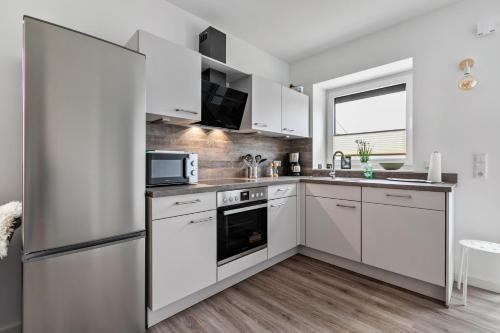 a kitchen with white cabinets and a stainless steel refrigerator at Mika in Oesterdeichstrich