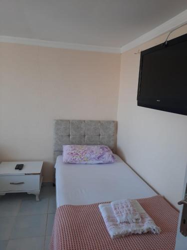 a bedroom with a bed and a flat screen tv at Beyaz Apart Pansiyon in Cesme