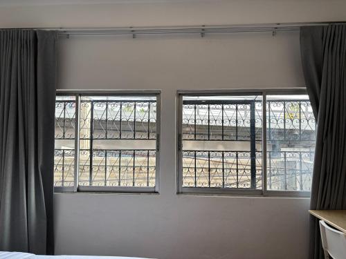two windows in a room with a bed in front at M3 Bangkok Bake & Bed in Bangkok