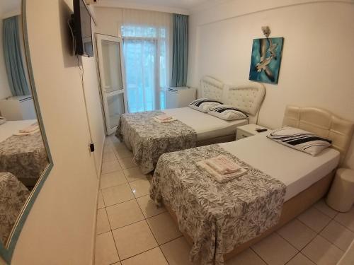 a hotel room with three beds and a television at Beyaz Apart Pansiyon in Cesme