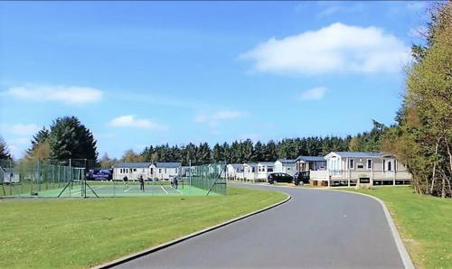 a park with a tennis court and a basketball hoop at Private Hot Tub & Spacious Decking Area in Northumberland, Dog-Friendly, Free Golf Access in Swarland