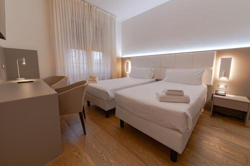 a hotel room with two beds and a desk at Hotel Mercure Milano Solari in Milan