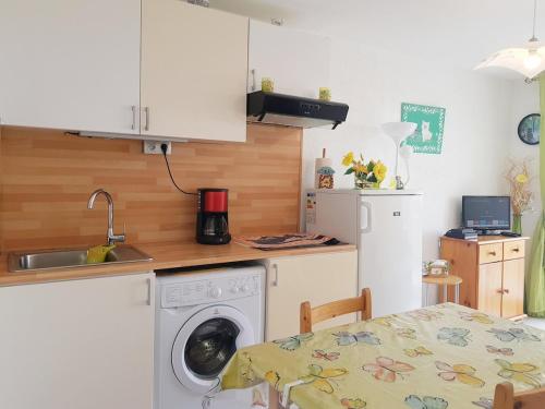 une cuisine avec une machine à laver et une table dans l'établissement Appartement 4 personnes avec terrasse, parking et piscine collective - V0784, à Vias