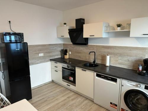 a kitchen with a black refrigerator and a dishwasher at Yellow one in Magdeburg