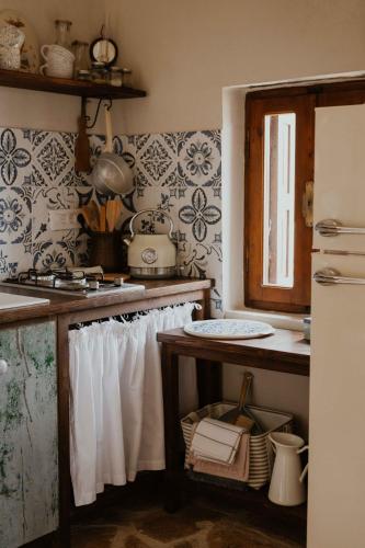 a kitchen with a counter with white curtains and a refrigerator at Ewas Cretan Vintage Houses- Pet Friendly in Kharkhalianá