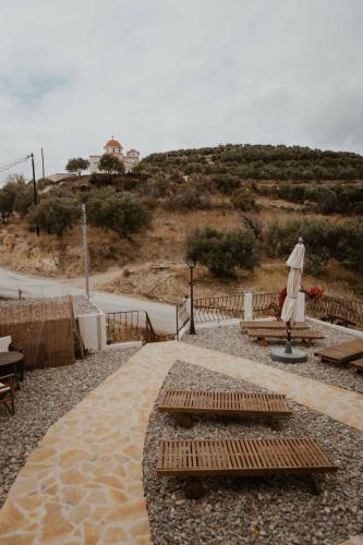 a patio with benches and an umbrella on a beach at Ewas Cretan Vintage Houses- Pet Friendly in Kharkhalianá