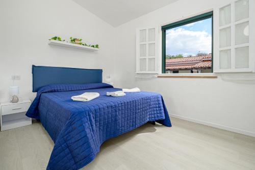 a bedroom with a blue bed with towels on it at I giardini di Cala D'ambra in San Teodoro
