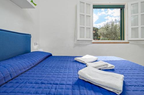 a blue bed with two towels on top of it at I giardini di Cala D'ambra in San Teodoro