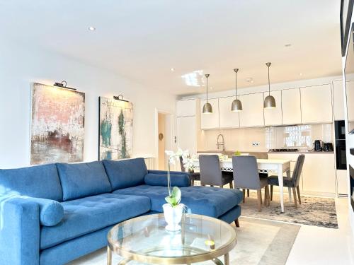 a living room with a blue couch and a table at Stylish Apartment with BBQ Kensington in London