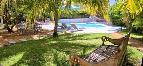 a park bench sitting in the grass next to a pool at LAKAZ DEL SOL - Modern and elegant apartments with luxurious garden, pool and barbecue area - Tourism Permit Certified in Tamarin