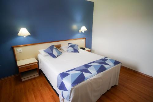 a bedroom with a large bed with blue walls at Hotel Dan Inn Sorocaba by Nacional Inn in Sorocaba