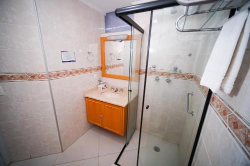 a bathroom with a shower and a sink and a mirror at Hotel Dan Inn Sorocaba by Nacional Inn in Sorocaba