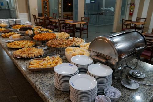 a buffet of food on a table with plates at Hotel Dan Inn Sorocaba by Nacional Inn in Sorocaba