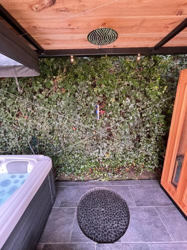 an outdoor shower with a bush with a hot tub at Loft du presbytère - Calme et nature in Beauraing