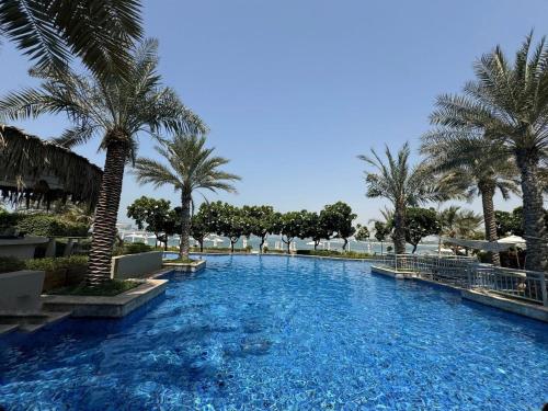 a large swimming pool with palm trees in a resort at Bright 2 Bedroom Apartment, Beach & Pool Access in Dubai