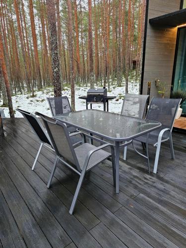 a table and chairs on a deck with a grill at Beach house in Lohusalu - for extra cost sauna and barrel bath in Laulasmaa