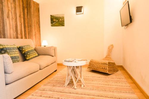 ein Wohnzimmer mit Sofa und Tisch in der Unterkunft LA FERME DU MARAIS GIRARD (Villas) in Brétignolles-sur-Mer