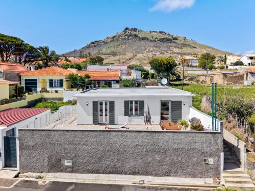 ein weißes Haus mit einem Hügel im Hintergrund in der Unterkunft Casa do Cabeco in Vila Baleira